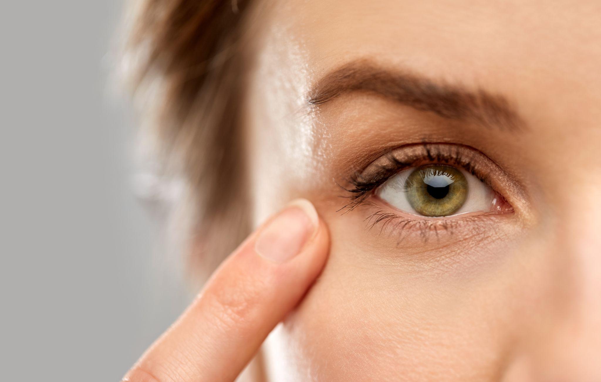 close up of woman pointin finger to eye