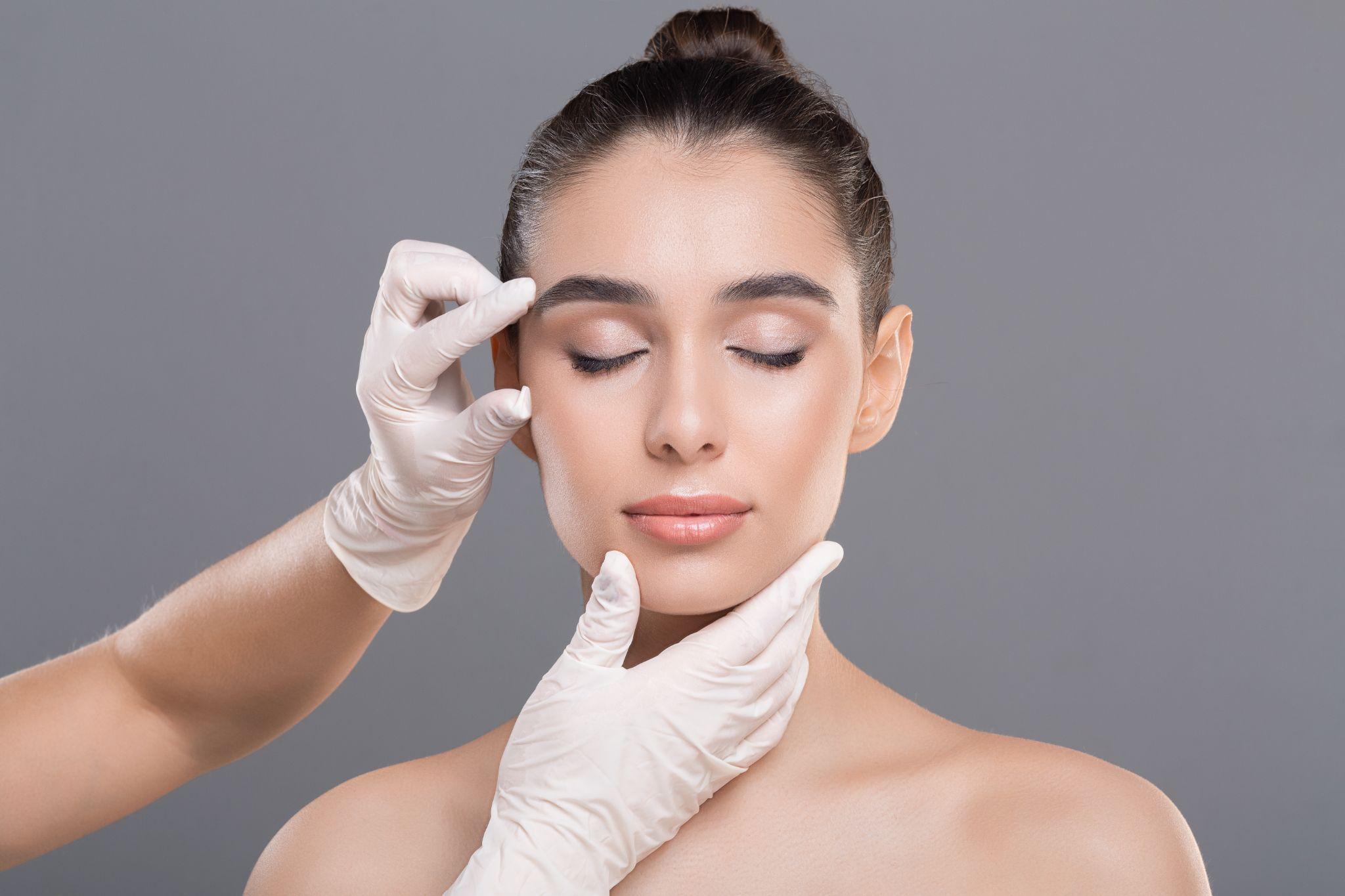 Cosmetologist examining facial wrinkles on young woman face