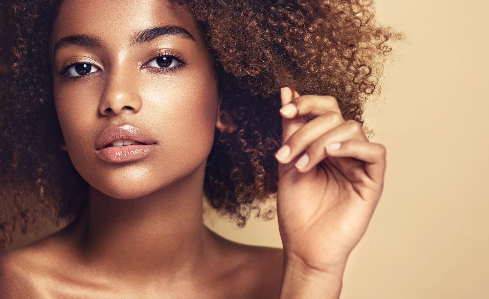 Beauty portrait of african american woman with clean healthy skin on beige background.